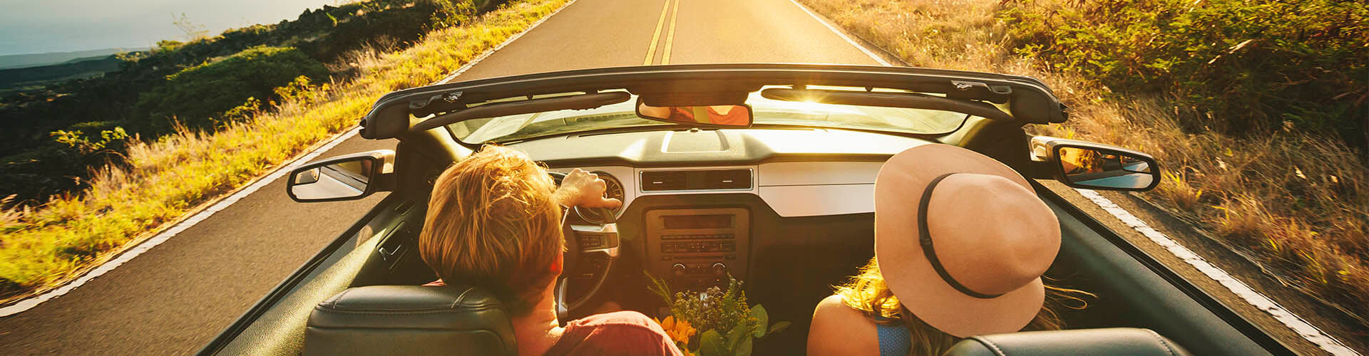 Seguro del Automóvil - Pareja feliz conduciendo por la carretera en su coche descapotable