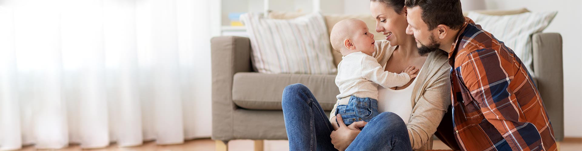 Seguros para Particulares - Familia con bebe sentados en el suelo del salon de su casa jugando