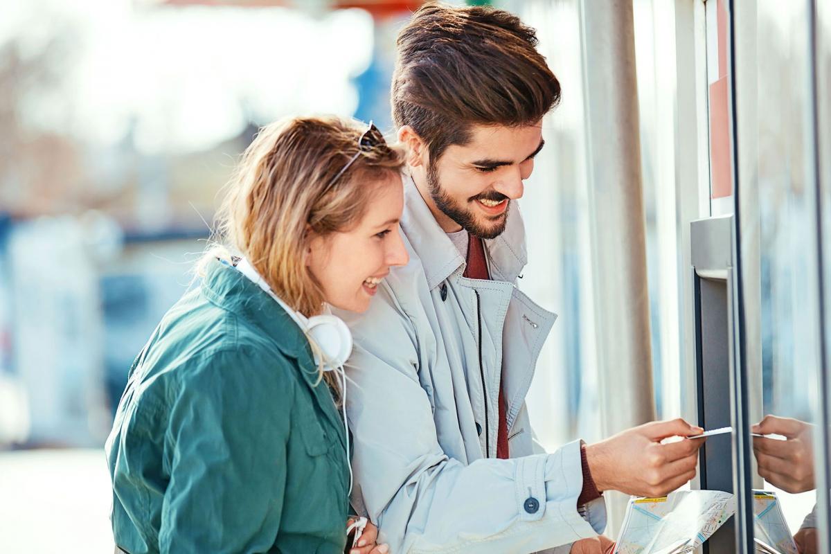 Dos personas contentas sacando dinero del cajero