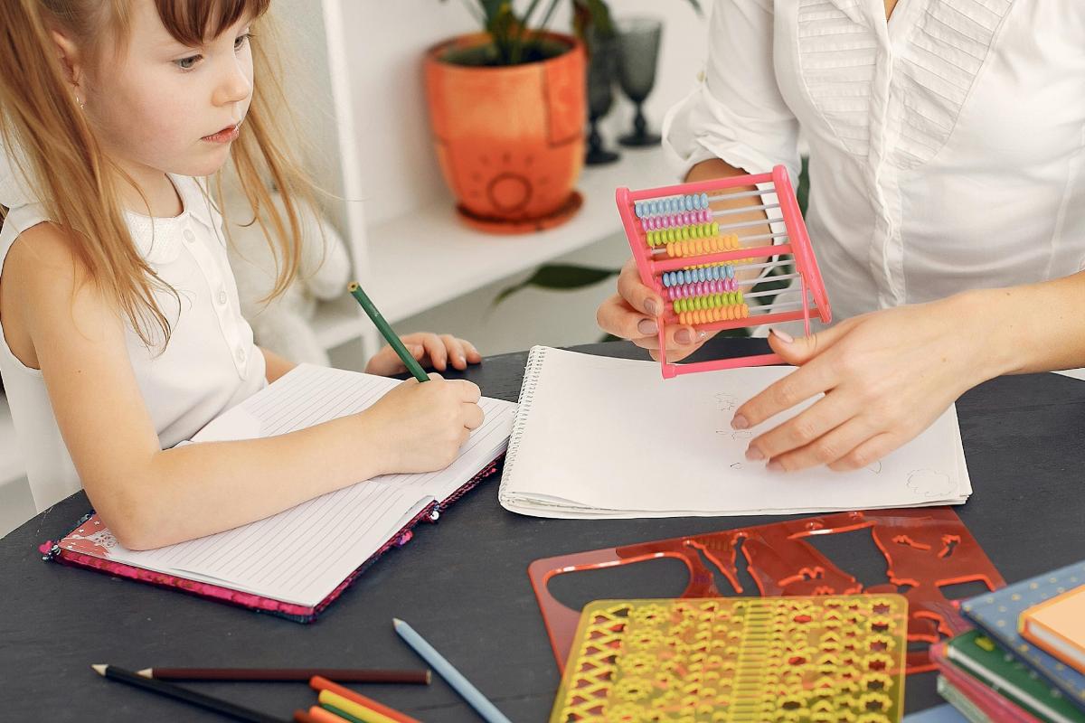 Mujer y niña con lápiz en el colegio